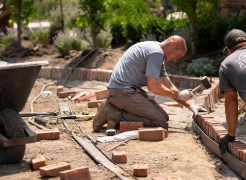 Two landscaping technicians laying bricks for residential project
