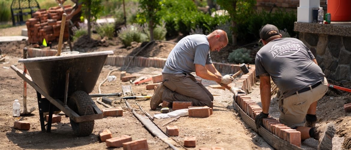 Two landscaping technicians laying bricks for residential project