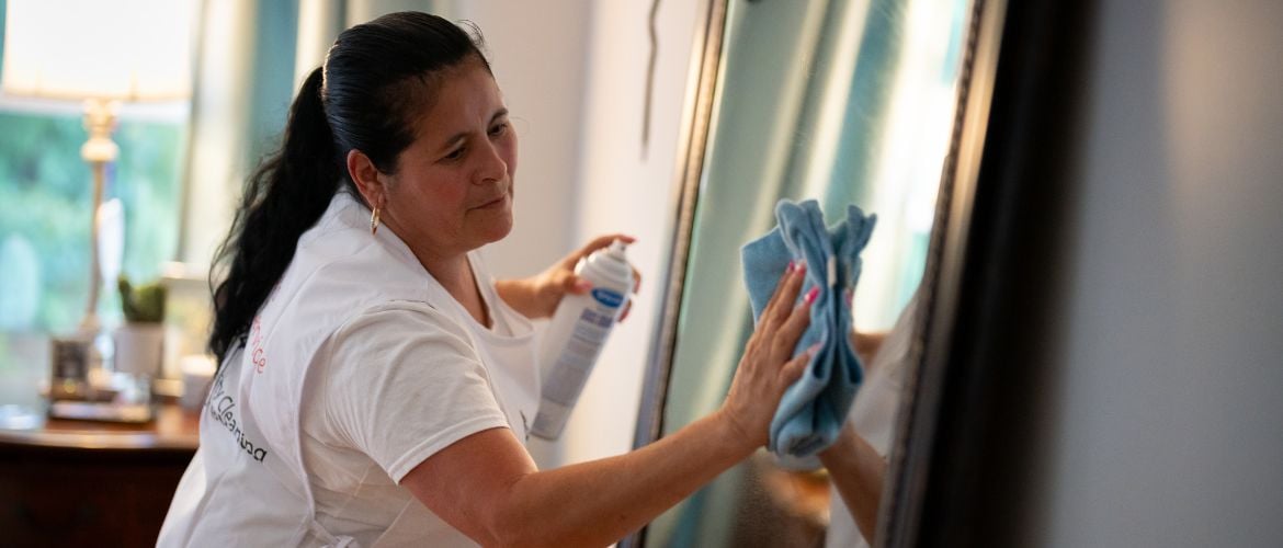 Cleaning service provider cleaning mirror with microfibre cloth