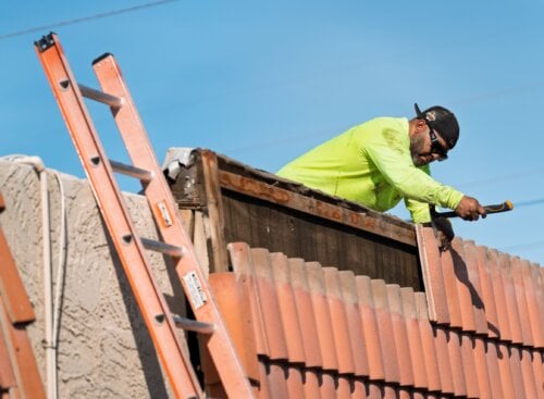 image of roofer installing tiles on roof