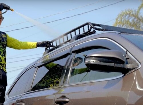 Car detailer power washing the roof of a SUV