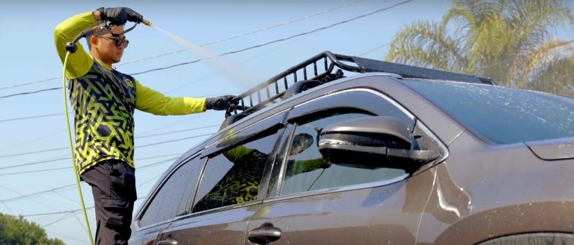 Car detailer power washing the roof of a SUV