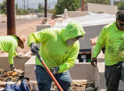Roofing service providers clearing debris on a rooftop.