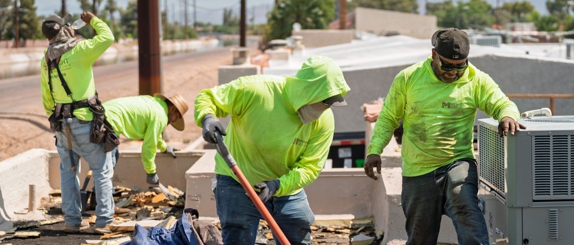 Roofing service providers clearing debris on a rooftop.