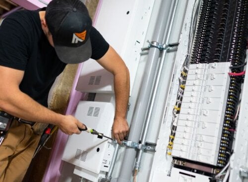 Electrician working on wiring inside a breaker panel