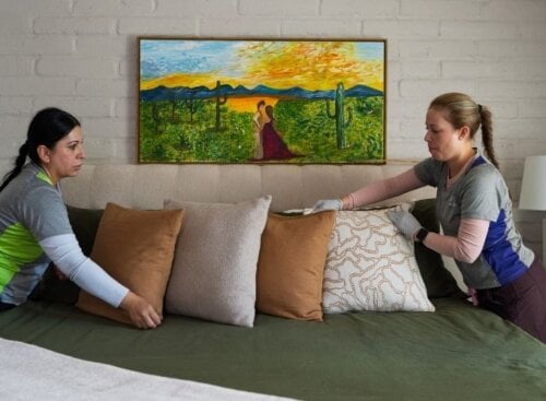 Two house cleaners making a client's bed.