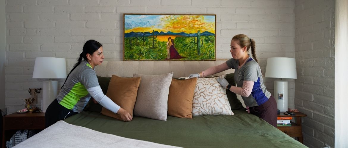Two house cleaners making a client's bed.