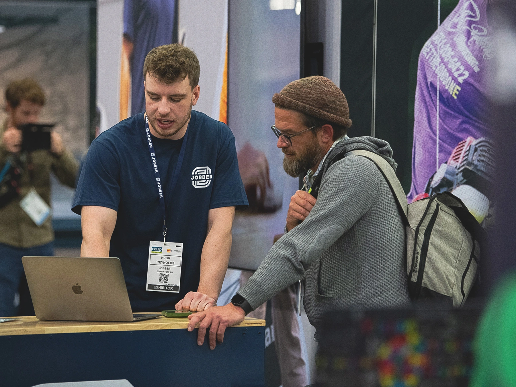 Two people looking at a laptop at a trade show.