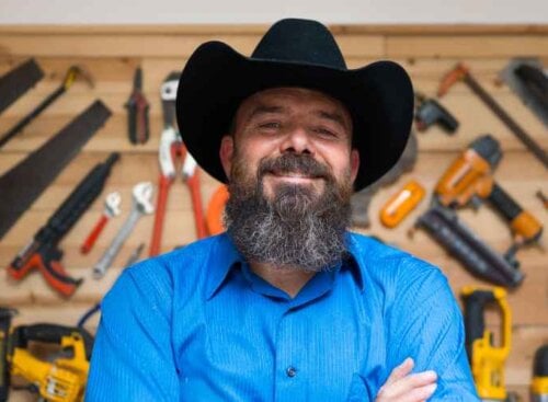 Portrait of a handyman standing in front of a wall of tools.