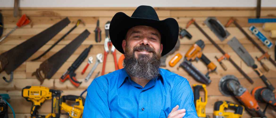 Portrait of a handyman standing in front of a wall of tools.