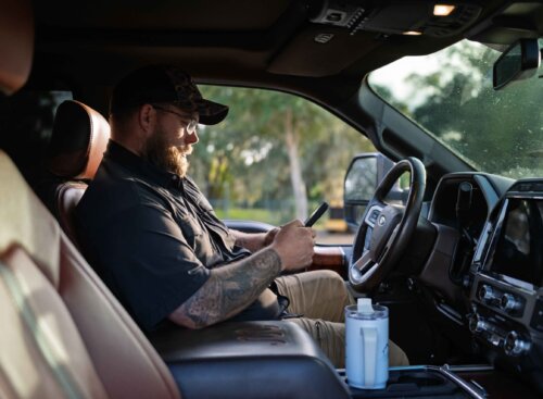 Chris Chase of Grass checking job information on a smartphone inside a work truck