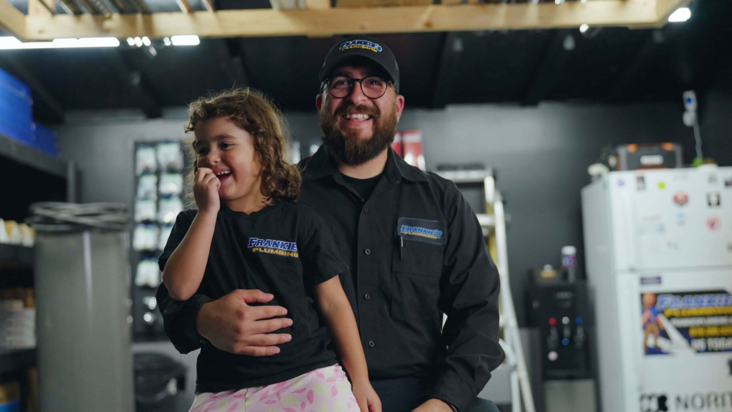 Frankie’s Plumbing business owner with family while sitting inside a workshop.