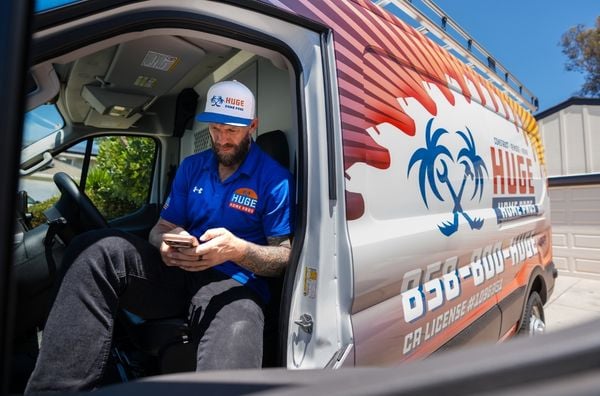 Service provider checking his phone while seated in a wrapped van.