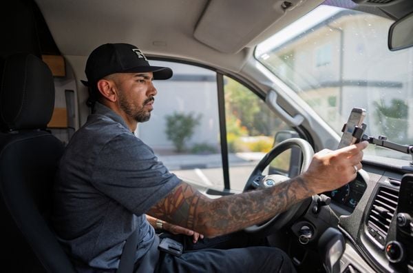 Service provider checking his phone while seated in his work vehicle.